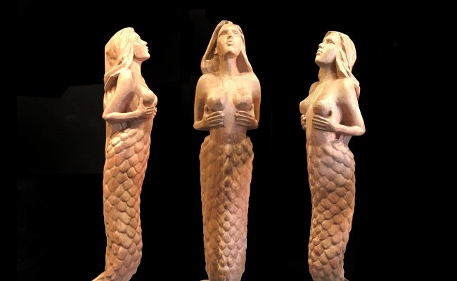Three mermaid models in wood.